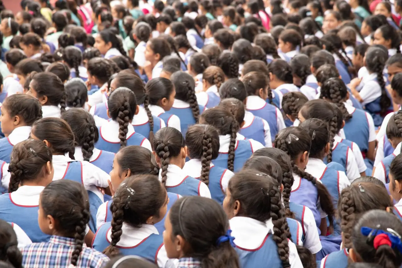 Rows of schoolgirls in uniform seen from behind at a morning assembly